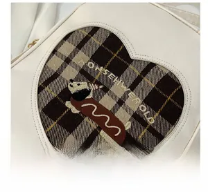 Detail of heart-shaped cutout with puppy embroidery and plaid fabric on white backpack