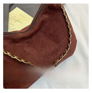 Detail of dark brown suede shoulder bag with chunky gold metal chain strap and zip closure
