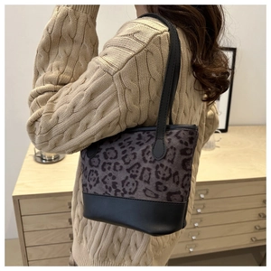 Detail shot of leopard print patchwork shoulder bag worn by model in a cozy knit sweater