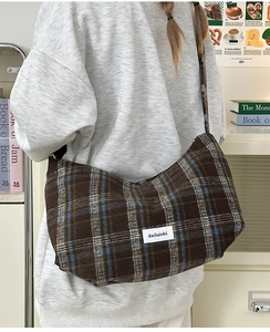 Detailed close-up of brown plaid wool crossbody bag with classic brand woven label
