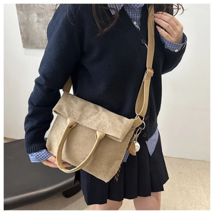Detail of khaki canvas tote bag with leather handle and decorative baseball pendant