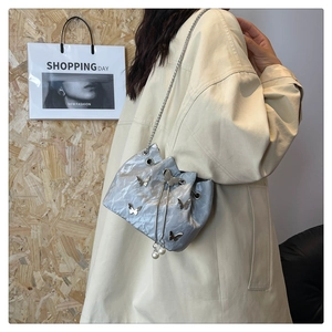 Détail du sac seau plissé argenté avec papillons métalliques et bandoulière perle