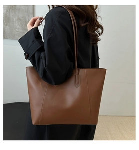 Detail of classic brown leather tote bag with stitching and slender double shoulder straps