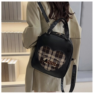 Detail view of heart-shaped plaid pattern and cartoon puppy print on a black PU backpack