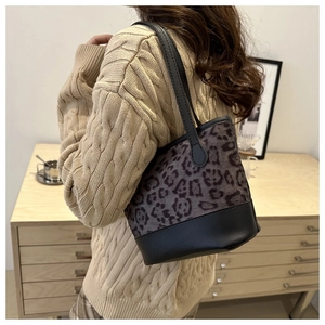 Detail of leopard print bucket bag with plush gray texture and black leather strap