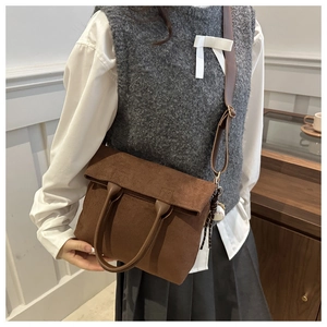 Detailed view of brown corduroy tote bag with leather straps and baseball charm detail