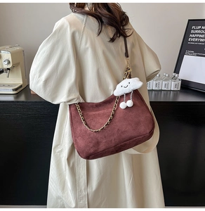 Detail of burgundy faux suede shoulder bag with gold chain and white cloud charm decoration