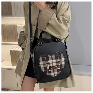 Detail of checkered heart patch with cute puppy embroidery on a black shoulder bag