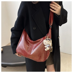 Detail view of burgundy tote bag showing soft oil-wax leather texture and shoulder strap