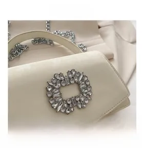 Detail of elegant cream leather handbag featuring a crystal square buckle and silver chain