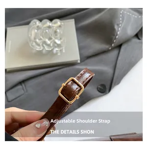 Détail d'une bandoulière en cuir PU marron réglable avec boucle dorée et coutures fines