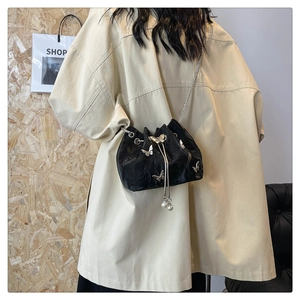 Détail du sac seau noir plissé avec des breloques papillon argentées et une chaîne fine