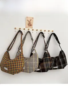 Detailed view of four plaid wool dumpling bags hanging on white wooden wall hooks