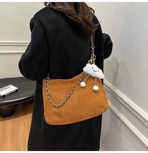 Detail of brown suede crossbody bag with gold chain strap and plush cloud charm