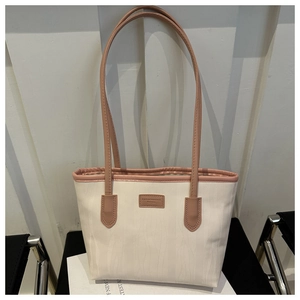 Detailed close-up of large canvas tote bag with contrast handles and leather logo patch