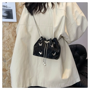 Détail du sac seau plissé noir avec papillons argentés et détails de perles de cordon
