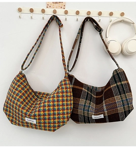 Detailed view of plaid wool dumpling bags with adjustable straps and woven labels