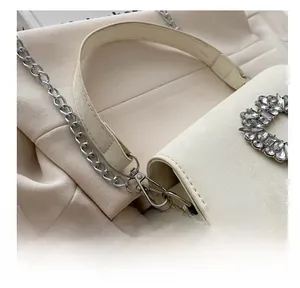 Detail of silver metal hook and chain with sparkling rhinestone flower on cream leather bag