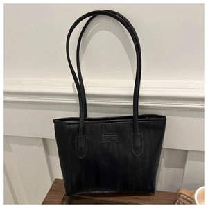 Detail of black PU leather tote bag with vertical wave texture and fashion logo patch
