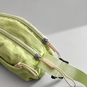 Dettaglio della borsa in nylon verde chiaro con doppie cerniere e cordoncini kaki lunghi