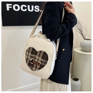Detail of white backpack featuring heart-shaped plaid patchwork and cartoon puppy embroidery