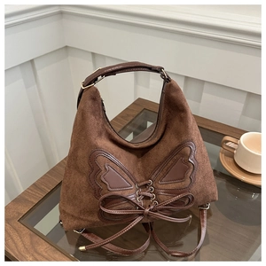 Detailed view of brown suede handbag with leather bow and metallic gold accents
