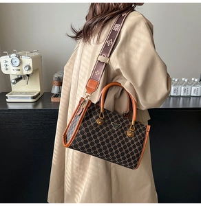 Detail of vintage brown textured crossbody bag with metal logo and wide patterned strap