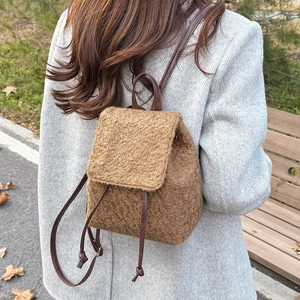 Brown fleece backpack with faux leather straps shown on a model in a grey wool coat