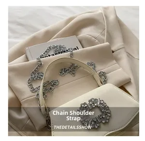 Close-up of cream square bag with silver chain strap and sparkling rhinestone detail