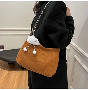 Detail of caramel suede hobo bag with metal chain strap and white plush cloud charm