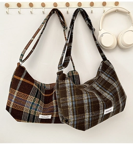 Detail view of plaid wool dumplings bags in autumn colors hanging on a wooden hook rack