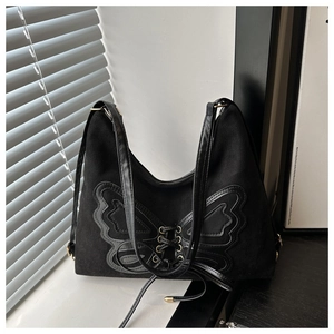 Detailed close-up of a large bow design with lace-up eyelets on a black canvas tote bag