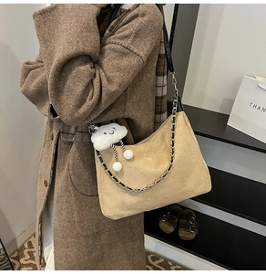 Detail of khaki suede shoulder bag with gold chain strap and cute cloud charm on a model