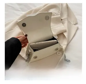 Detail showing internal capacity of the off-white crossbody bag with silver magnetic snaps