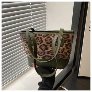 Detail of leopard print tote bag featuring green leather straps and fuzzy fabric texture