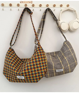 Close-up of textured plaid dumpling bags with wide straps and minimalist fabric labels