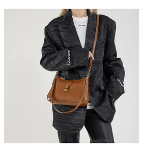 Détail du sac vintage en cuir marron avec boucle en métal doré porté par un mannequin
