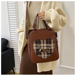 Detail of vintage brown leather bag with heart-shaped window and plaid puppy embroidery