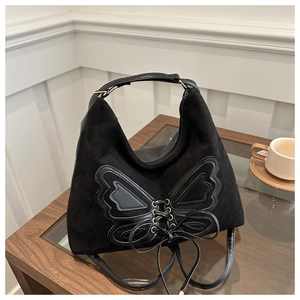 Detail of black bow-knot shoulder bag featuring vintage matte texture and long tassels