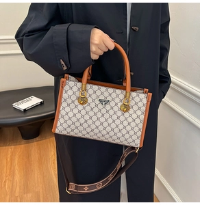 Detail of monogram tote bag with caramel leather handles and a printed wide strap