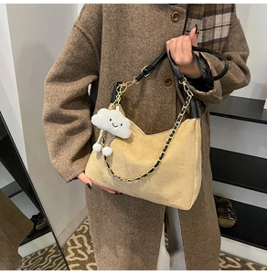 Detail of beige corduroy shoulder bag featuring black leather strap and gold chain accent