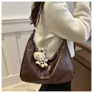 Macro detail of deep brown large capacity PU leather hobo bag with zip and plush charm