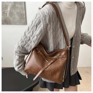 Braune Vintage-Hobo-Tasche aus Kunstleder, getragen vom Modell, zeigt Seitenprofil und Kapazität