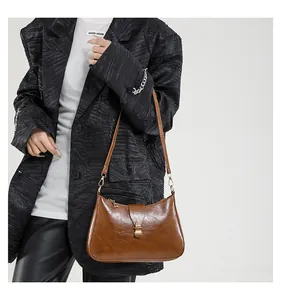 Détail du sac croissant vintage marron avec texture brillante et boucle en laiton