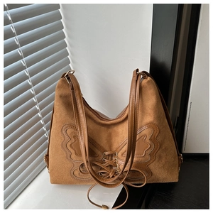 Macro detail of the brown suede tote bag with large decorative leather butterfly and laces