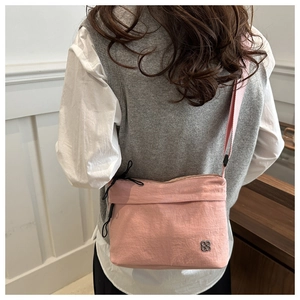 Close-up of pink nylon crossbody bag with silver clover logo and adjustable wide strap