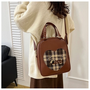 Close-up of vintage brown leather and plaid backpack with cute puppy heart window detail