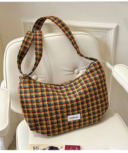 Close-up of multicolor plaid tweed fabric and brand label on a croissant shoulder bag