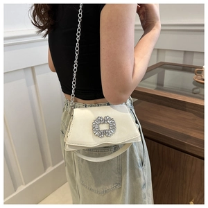 Detail of a cream faux leather shoulder bag featuring a large sparkling square rhinestone buckle