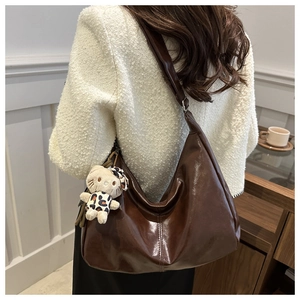 Detailed back view of a dark brown retro hobo bag with a plush charm on wide strap